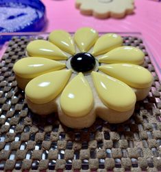 a yellow and black flower shaped cookie sitting on top of a table next to other cookies