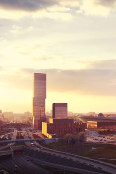 an aerial view of a city with tall buildings and traffic on the road at sunset