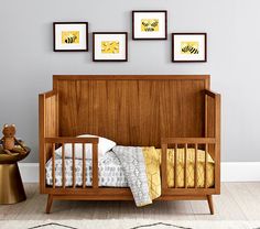 a baby crib in a room with three framed pictures on the wall above it