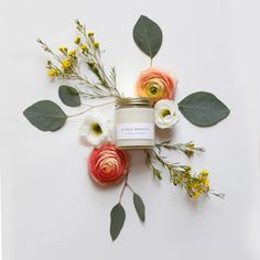 a candle surrounded by flowers and greenery on a white background with the word love written below it