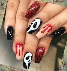 a woman's hand with red and black nail polish on it, decorated with skulls