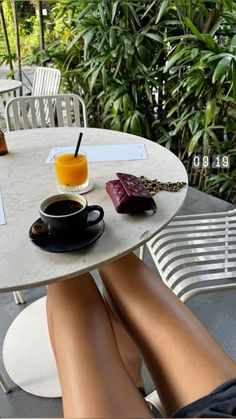 a person sitting at a table with their feet on the table and holding a glass of orange juice