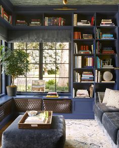 a living room with bookshelves, couch and coffee table in front of a window