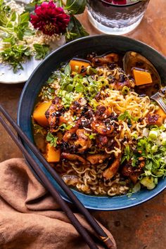 a bowl filled with noodles and vegetables next to chopsticks