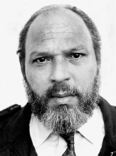 a black and white photo of a man with a beard wearing a vest and tie