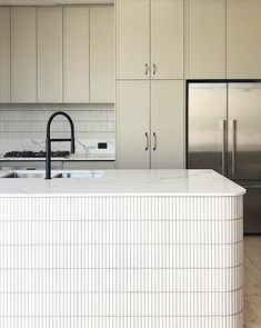 a white kitchen with stainless steel appliances and cabinets in the back drop off area is shown