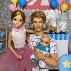 two dolls are standing next to each other in front of a table with balloons and streamers