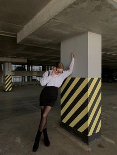 a woman is leaning against a pole and talking on her cell phone while wearing a skirt