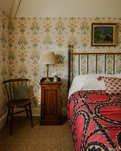 a bedroom with floral wallpaper and a bed in the corner next to a night stand