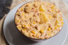 a white plate topped with a bowl filled with corn and meat chow meinon soup