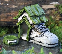 a shoe with a house made out of it sitting on top of a rock in the grass