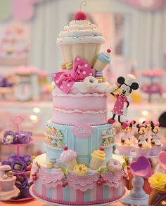 there is a very large cake decorated with minnie mouses and cupcakes on it