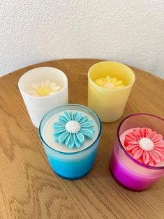 three different colored vases sitting on top of a wooden table with flowers in them