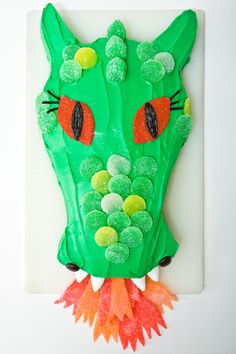 a paper plate with a green cat mask on it's face and some gummy balls in the mouth