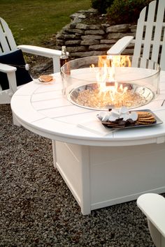 an outdoor fire pit with chairs around it and graveled area in the back ground