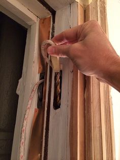 a hand is holding a piece of rope in front of an open door that has been stripped off