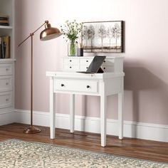 a white desk with a laptop on top of it in front of a pink wall