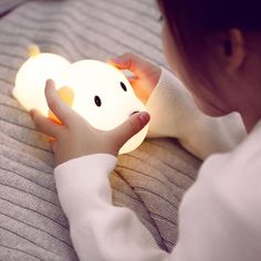 a young child is playing with a light up elephant toy on the bed in front of her