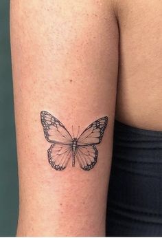 a small butterfly tattoo on the right side of the left arm is shown in black ink