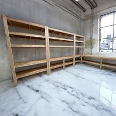 an empty room with wooden shelves in the middle and marble flooring on the other side