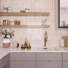 a kitchen with pink tiles and gold accessories on the countertop, along with wooden shelves