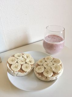 two sandwiches with banana slices and peanut butter are on a plate next to a glass of pink smoothie