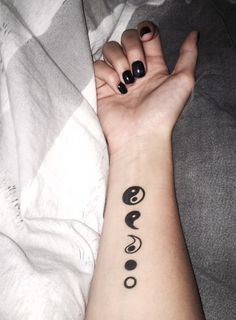 a woman's arm with black and white tattoos on her left wrist, which has the word peace written in cursive letters