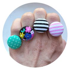 three different colored pins sitting on top of a persons hand in front of a white circle