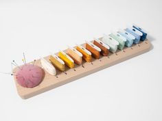 a row of different colored needles sitting on top of a wooden holder with a ball