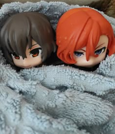 two dolls are sitting next to each other on a blanket