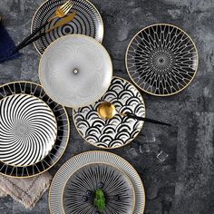 black and white plates with gold accents on a gray tablecloth next to utensils