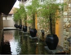 a row of black vases sitting next to each other on top of a pond