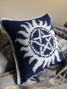 a blue and white crocheted pillow sitting on top of a bed