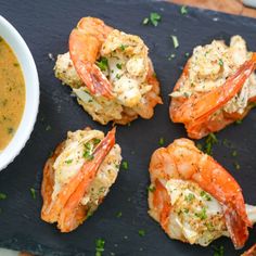 four pieces of cooked shrimp on a slate board next to a bowl of soup