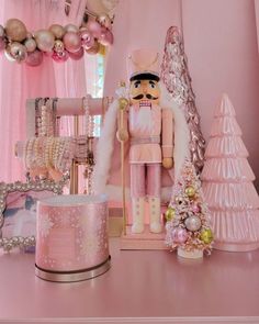 a nutcracker is sitting on a pink table next to other ornaments and decorations