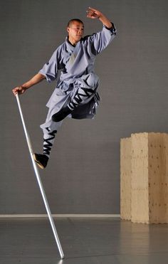 a man is doing tricks on a pole with one leg in the air and his other hand out