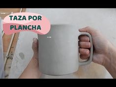 a person holding a white coffee mug in their hand with the words taza por plancha on it