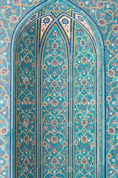 an intricately decorated wall in the middle of a building with blue and gold paint