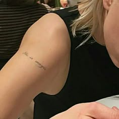 a woman with a small tattoo on her arm eating food at a table in a restaurant