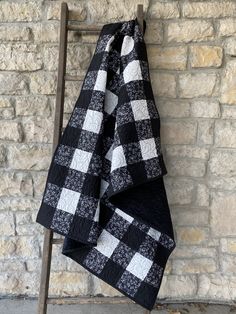 a black and white checkered blanket hanging on a clothes rack next to a brick wall