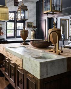 a large kitchen with marble counter tops and wooden cabinets, along with hanging lights above the sink