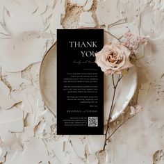 a black and white thank you card with a rose on it next to a plate