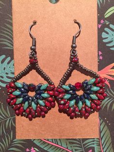 a pair of red, blue and green beaded earrings on top of a card