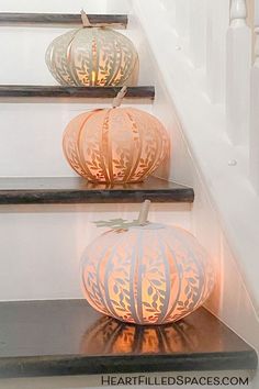 three decorative pumpkins sitting on top of a set of stairs with candles in them