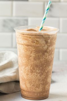 a cup with a straw in it sitting on a counter top next to a towel