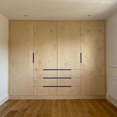 an empty room with wooden cabinets and hard wood flooring