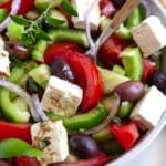 a salad with cucumbers, peppers, olives and tofu in it