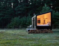 a small cabin in the woods is lit up at night with its windows open to reveal an outside bedroom