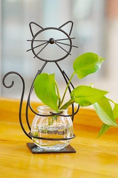 a glass vase with a plant in it and a cat figure sitting on top of it