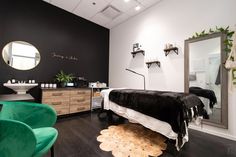 a black and white bedroom with green chairs in the corner next to a large mirror